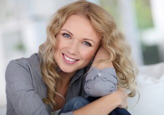 blond woman smiling leaning on elbow, Merrimack, NH | dental crowns and dental bridges